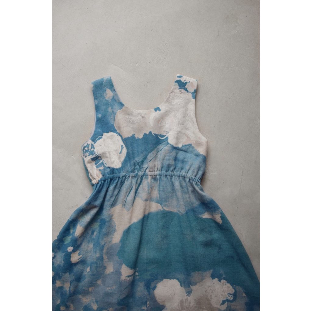 Partie haute d'une robe asymétrique cintrée bleue, à motif partiellement floral, sans manche.