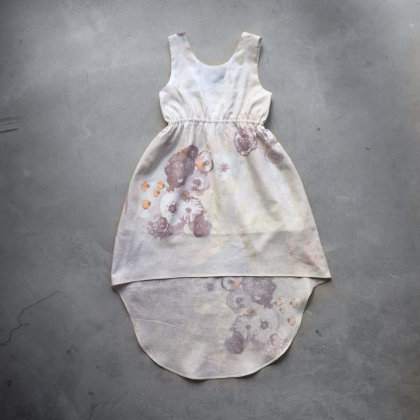 Robe asymétrique cintrée sans manche pour petite fille. Dans les tons écru avec un motif floral.