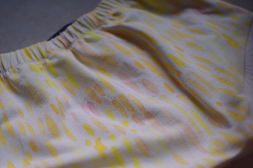 Détail du shorty pour bébé et petite fille en sweat moucheté à motif abstrait rose, orangé et jaune fluo.